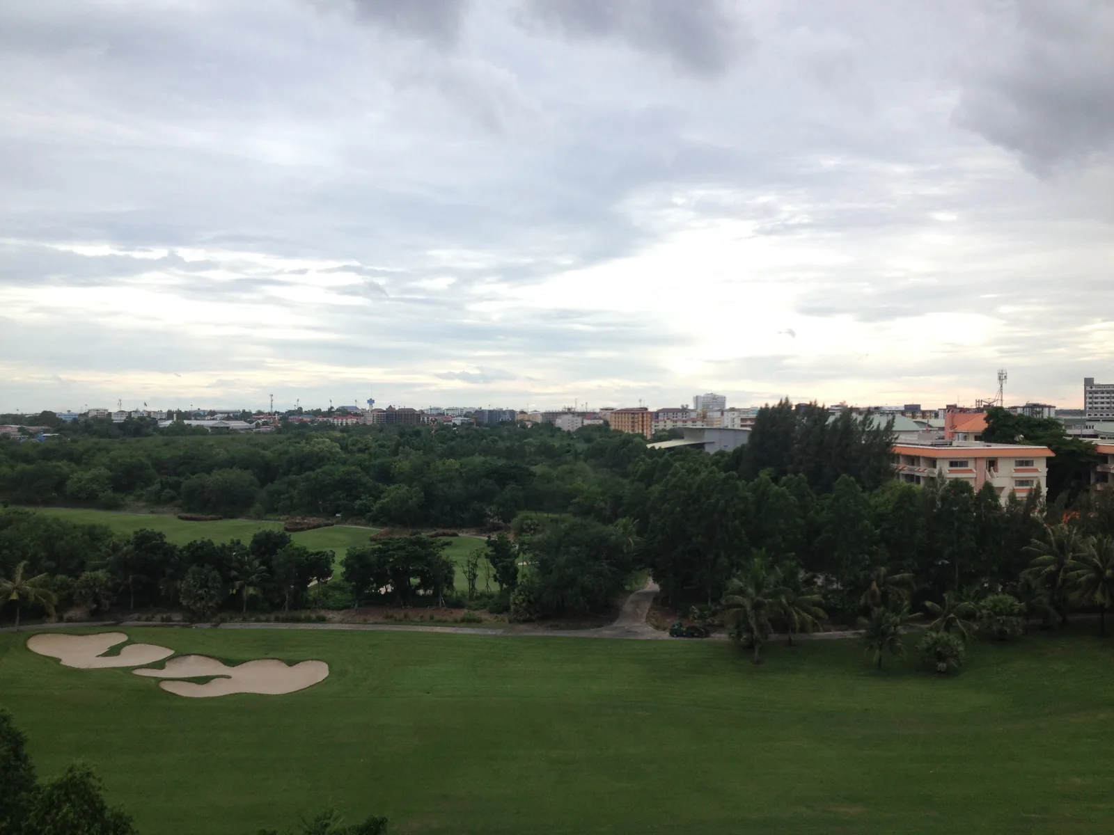 Amata Spring fairways and bunkers beneath a cloudy sky, with buildings beyond the trees, in June 2015.